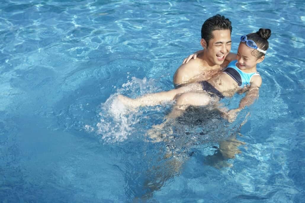 Father and daughter swimming at the pool